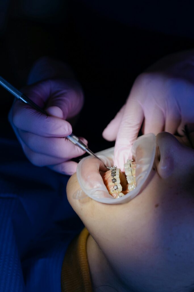Dentist performing procedure on patient with braces, highlighting dental care.